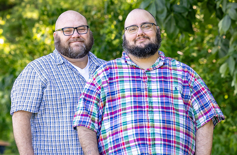 Jonathan Springborn standing next to his husband, Keller, in a park.
